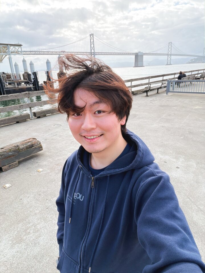 Minghan Zhu at the San Francisco waterfront with the Bay Bridge in the background.